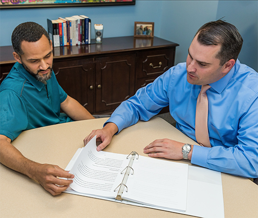 Employee benefits counselor discussing information with person in a wheelchair.