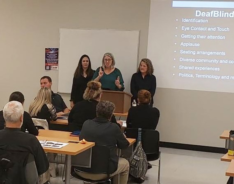 DSDHH Deaf/DeafBlind Services Coordinator Ashley Benton, flanked by sign language interpreters, leads a DeafBlind training