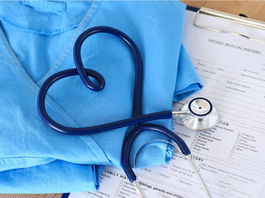 Image depicts a clipboard, blue nurse’s scrubs, and a stethoscope folded into the shape of a heart